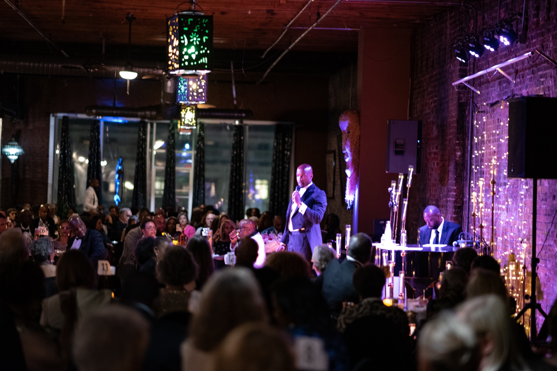 Elias Hendricks performing for a seated candlelit audience with his pianist