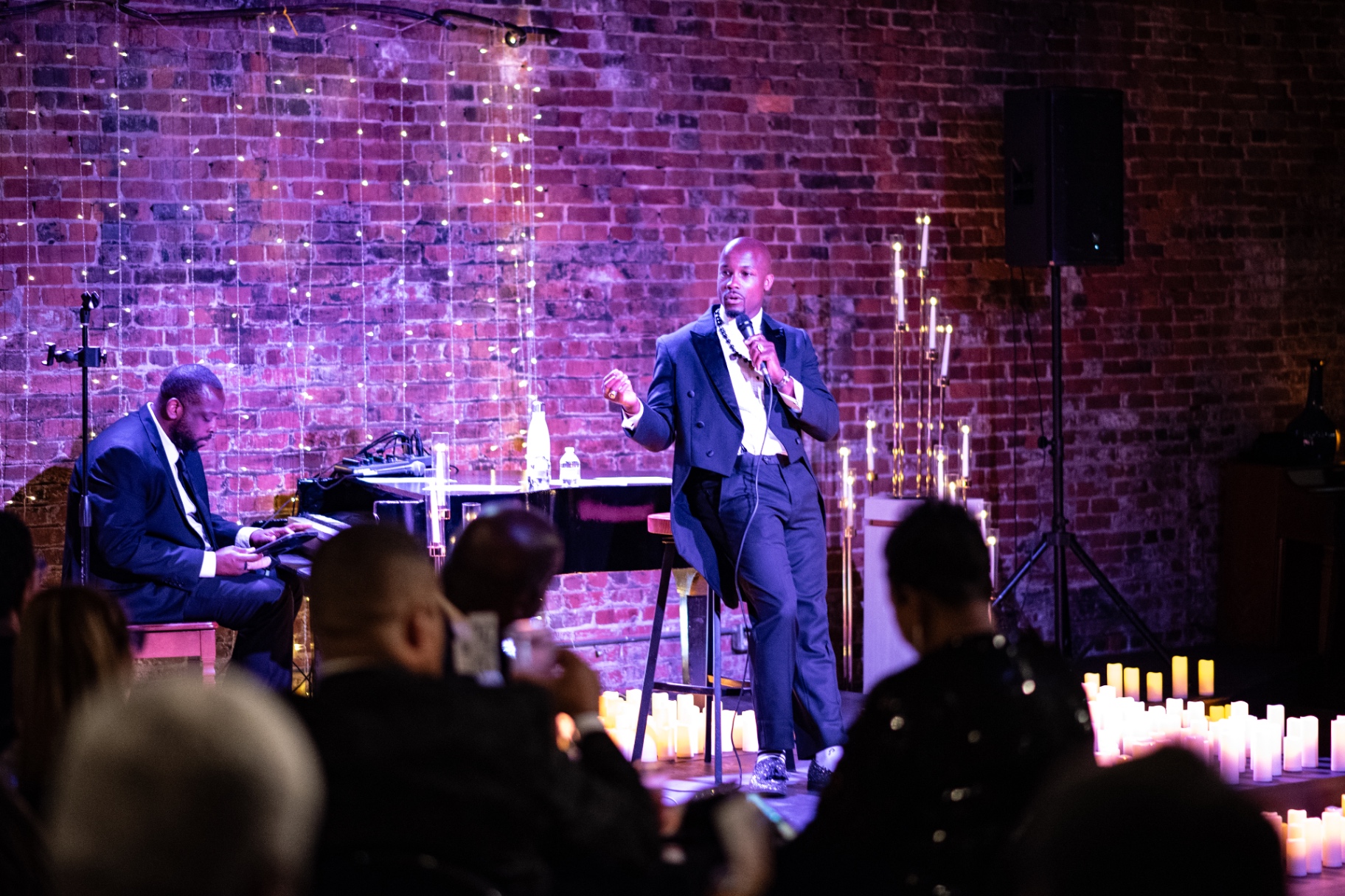 Elias Hendricks singing beside the grand piano as the audience watches