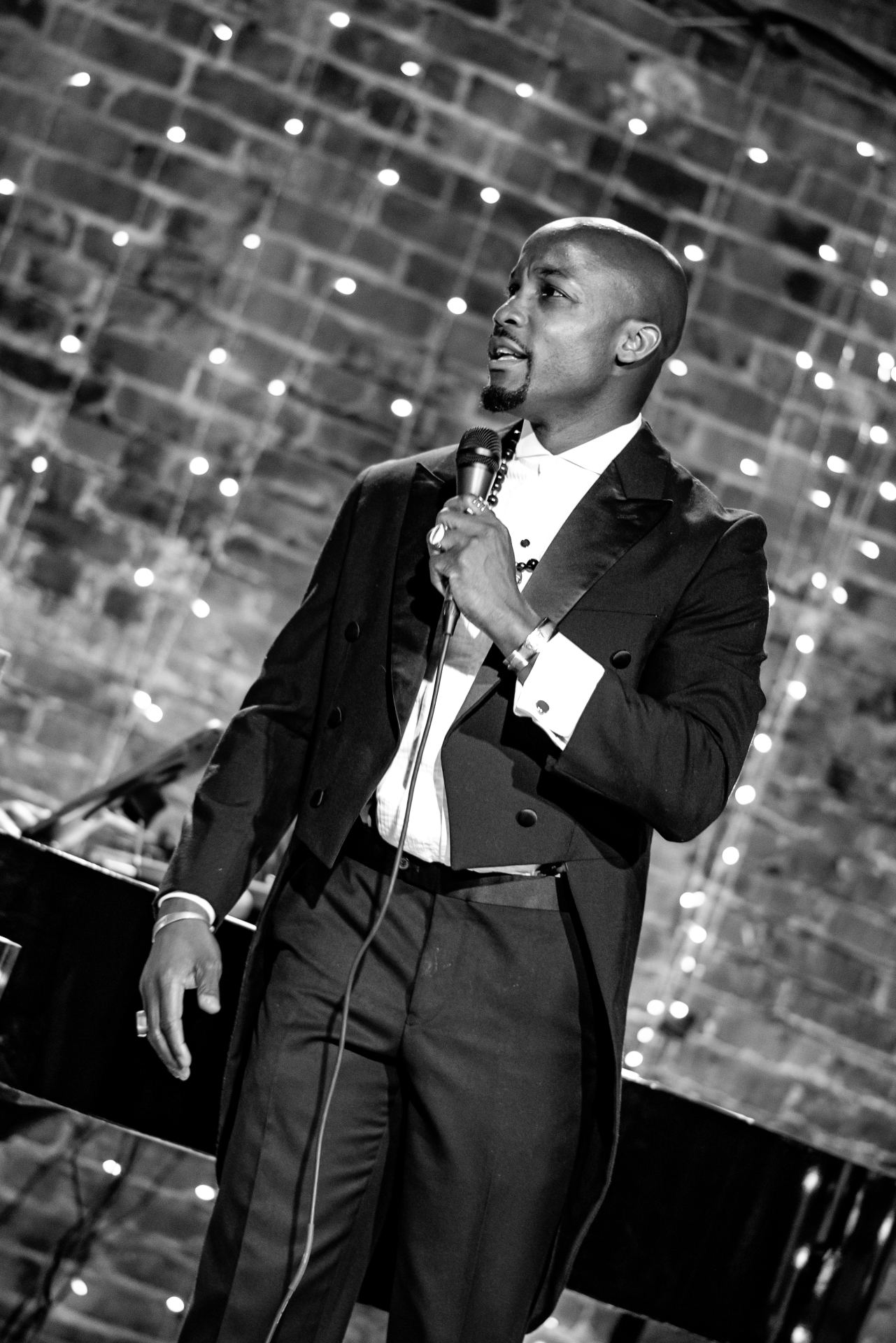 Black and white portrait of Elias Hendricks singing beneath string lights