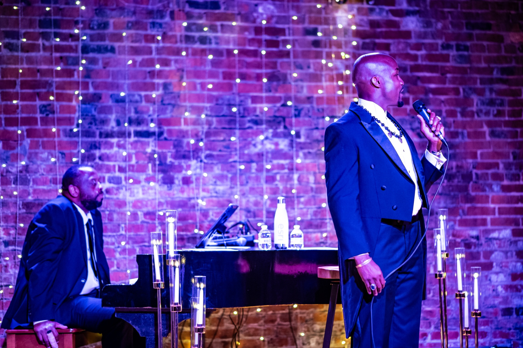 Elias Hendricks and his pianist on a candlelit stage with exposed brick