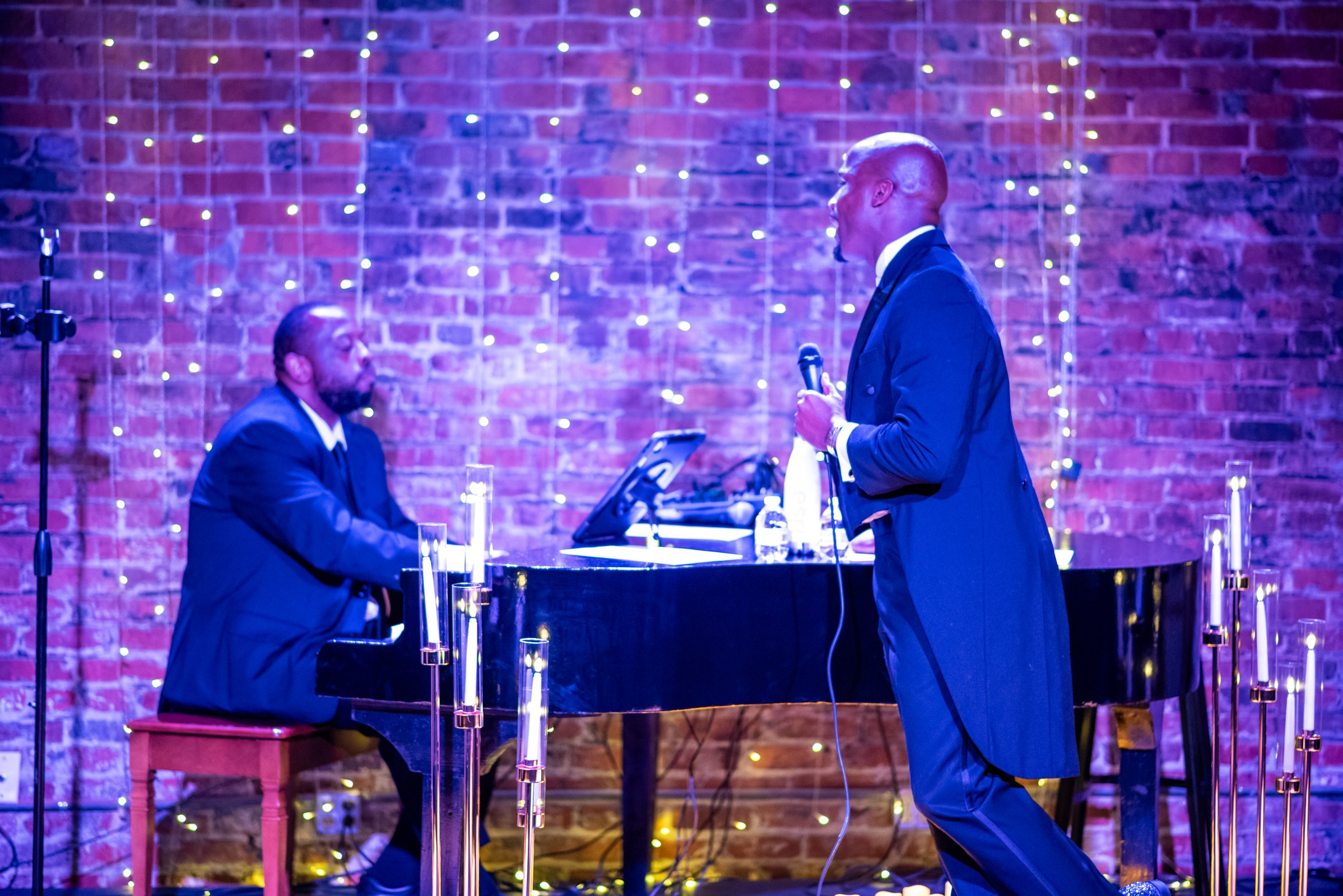 Elias Hendricks performing with a guest vocalist in an intimate candlelit room