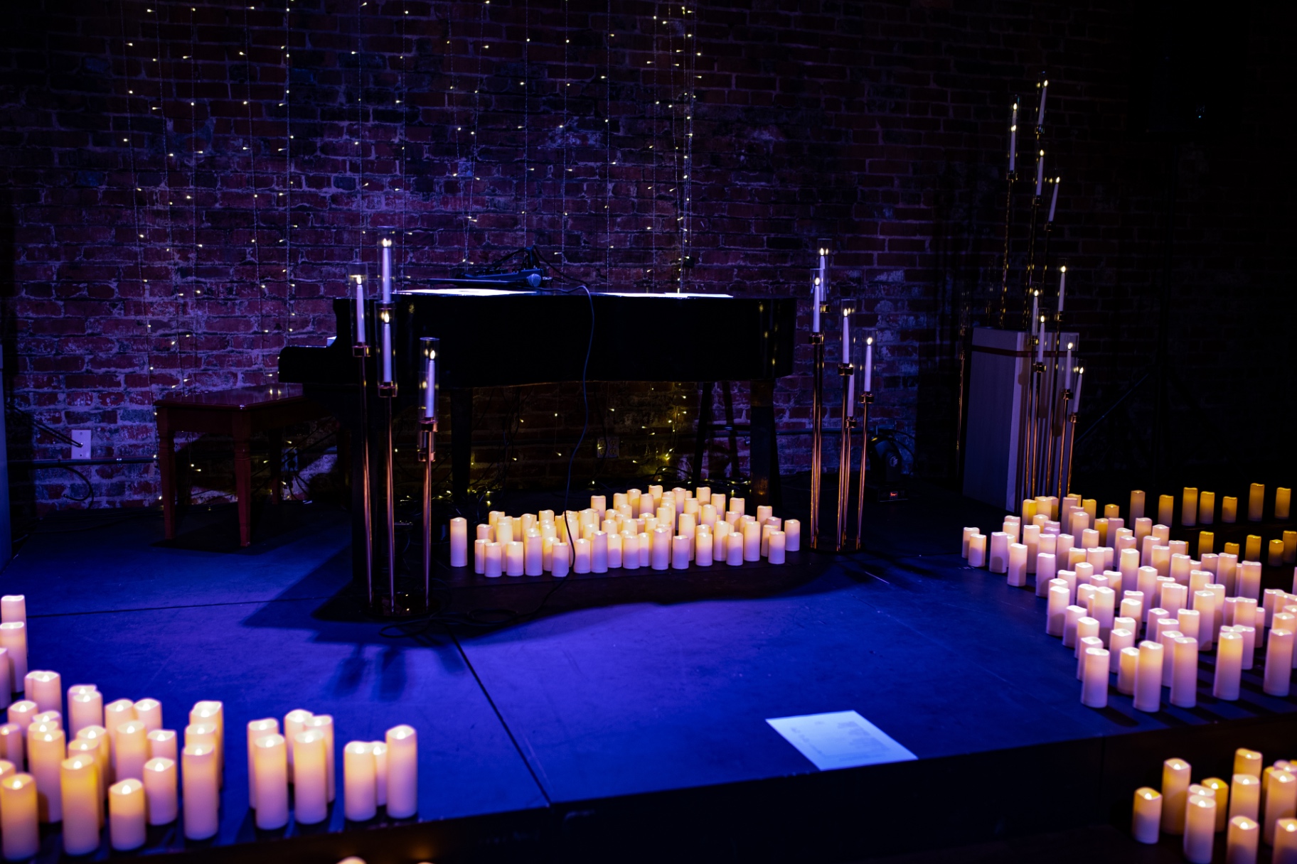 The candlelit stage before the show: grand piano, candles and string lights