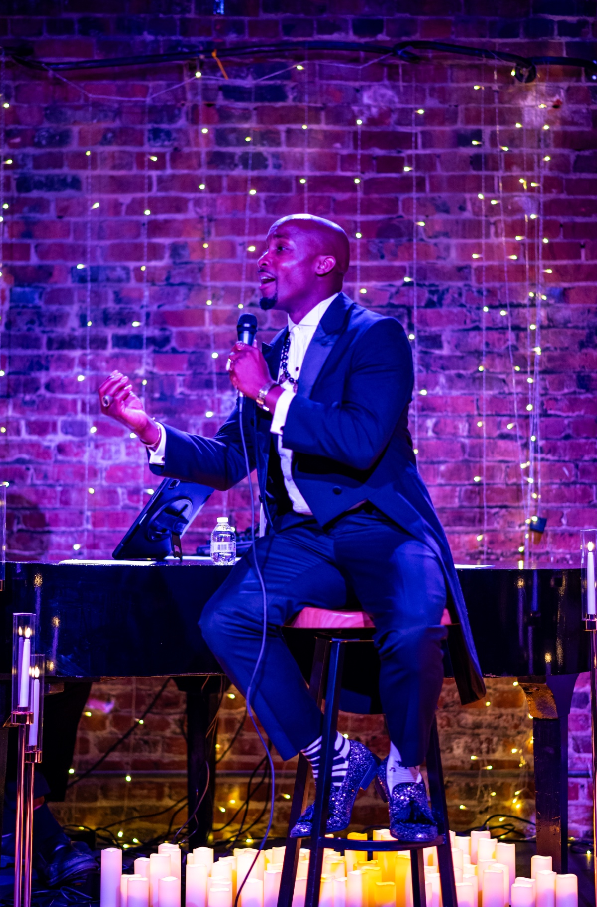 Elias Hendricks seated at the piano, singing to the candlelit room